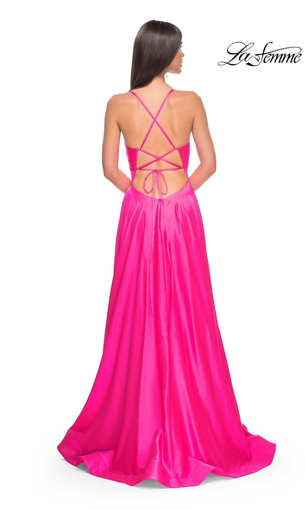 A woman is seen from behind wearing the La Femme Twist-Front Long A-Line Prom Dress 31412 in bright pink, featuring a crisscross open back and spaghetti straps. The La Femme logo appears in the top right corner.